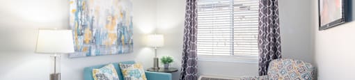 A living room with a blue couch, a patterned chair, and a small table.