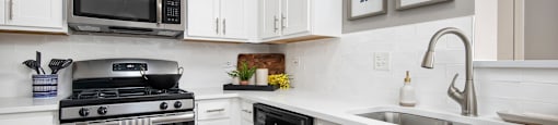 A kitchen with white cabinets and a black stove top oven.