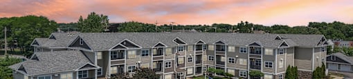 A large apartment complex with a parking lot in front.