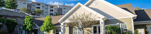 Exterior view of clubhouse and leasing office with apartment building visible on hill behind office at Summit Place apartments in Methuen, MA.