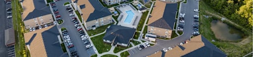 An aerial view of a residential complex with a swimming pool and surrounded by trees.