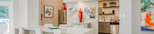 A modern kitchen with white bar stools and a white counter.