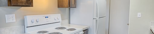 A kitchen with a white stove and wooden cabinets.