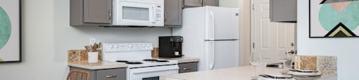 A kitchen with a white refrigerator, a white stove, and a white microwave.