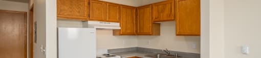 A kitchen with white appliances and wooden cabinets.