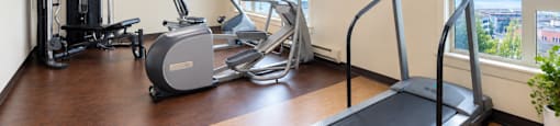 A treadmill is in the foreground of a well equipped gym.