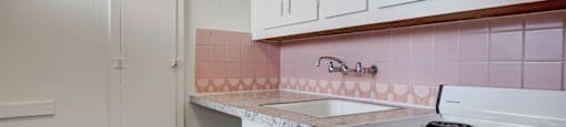 A kitchen with a white stove and white cabinets.