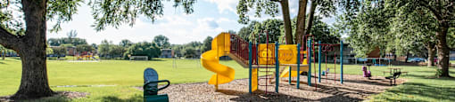 A playground with a yellow slide and a green toy chest.