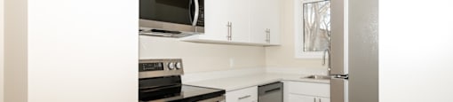 A kitchen with white cabinets and a black stove top oven.