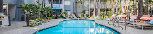 A round swimming pool surrounded by palm trees and lounge chairs.