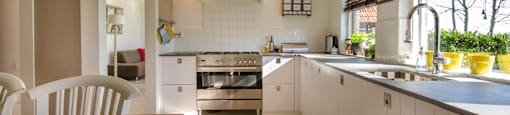 A modern kitchen with a wooden table and white cabinets.