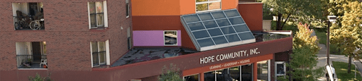 A building with a solar panel on the roof and the words "Hope Community, Inc." on the front.