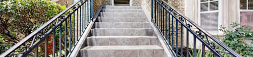 A set of stairs with a metal railing lead to a doorway.