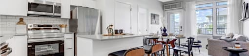 a living area with a kitchen and a dining area with bar stools