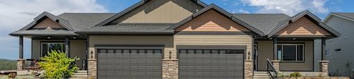 A duplex residence with a driveway and garage doors.