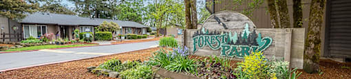 a community sign in front of a building with trees and a road