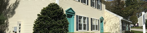A house with a green door and a green bush in front.