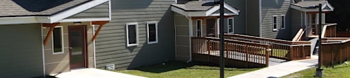 a row of houses with a yard and a bench at Conifer Woods Apartments, Homer