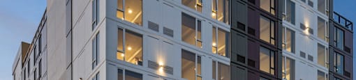 A modern multi-story building with a lot of windows and lights on.