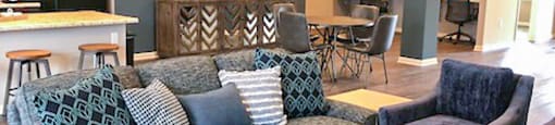 A living room with a grey couch and a glass coffee table.