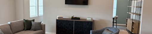 A living room with a grey sofa, a coffee table, and a television mounted on the wall.