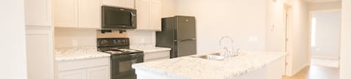 A kitchen with black appliances and white cabinets.