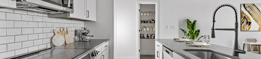 A modern kitchen with white cabinets and black countertops.