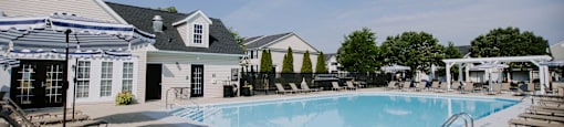 A swimming pool surrounded by sun loungers and umbrellas.