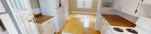 A kitchen with white appliances and wooden floors.