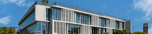 A modern building with a glass facade and a yellow crosswalk in front.