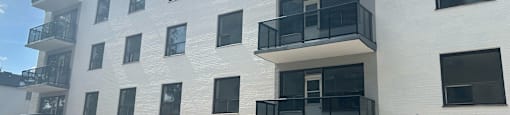 A white apartment building with black railings and closed grey garage doors.