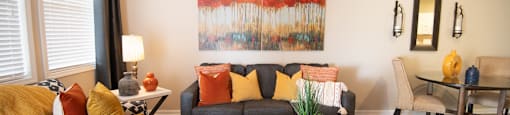 A living room with a couch, a chair, a coffee table, and a painting on the wall.