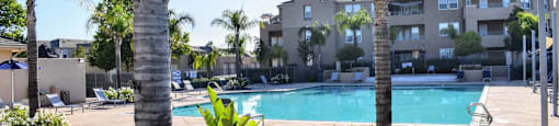 community pool with tropical landscaping and building in background