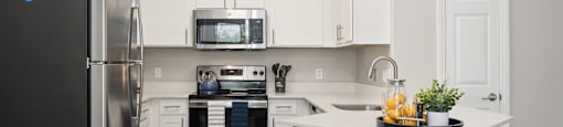 A kitchen with a black fridge, white cabinets, and a white island.