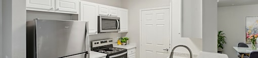 A kitchen with a stainless steel refrigerator, microwave, oven, and sink.