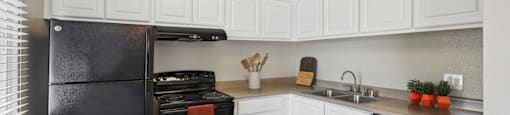 a kitchen with black appliances and a bowl of fruit