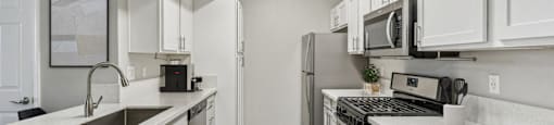 a spacious kitchen with white cabinets and stainless steel appliances