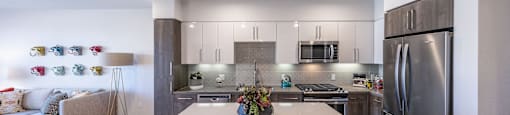 a kitchen with stainless steel appliances and a white island with four chairs