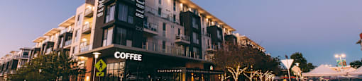 A coffee shop is located in a modern building with a black awning.