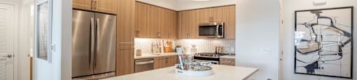 a kitchen with a large island and a stainless steel refrigerator