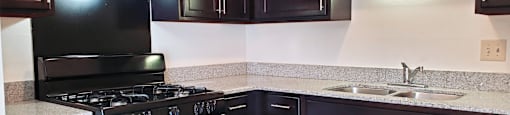 Kitchen in a 1 bedroom apartment with black appliances and dark wood cabinets at Carriage House West.