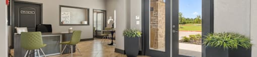 a lobby with glass doors and a table with chairs and a rug