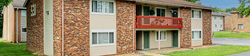A brick apartment building with a red balcony.