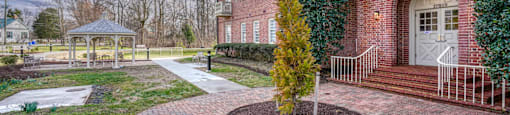 the front yard of a brick house with a gazebo and a pathway