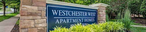 a sign apartments in front of plants and trees