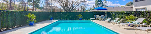 a swimming pool with chairs and umbrellas next to a house