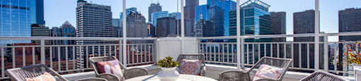 a rooftop patio with chairs and a table and a view of the city
