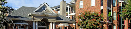 Luxury apartments in a gated community with red brick exteriors and beautiful landscaping at Prestonbridge Apartments in North Dallas