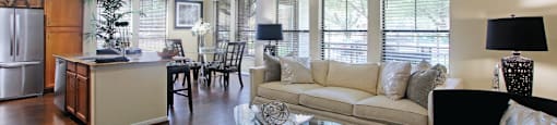 Luxury apartments in Houston with spacious open floor plan with granite countertops, kitchen island, stainless steel appliances, oversized windows, lots of natural light, and hardwood floors.