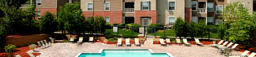 Resort-style pool with large sundeck, poolside lounge chairs, lush landscaping, beautiful landscaping, park-like setting with lots of trees at Breckenridge Apartments in southwest Omaha, Nebraska
